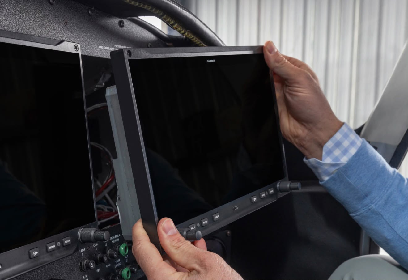 An AXIS flight display being fitted into an aircraft panel during installation.