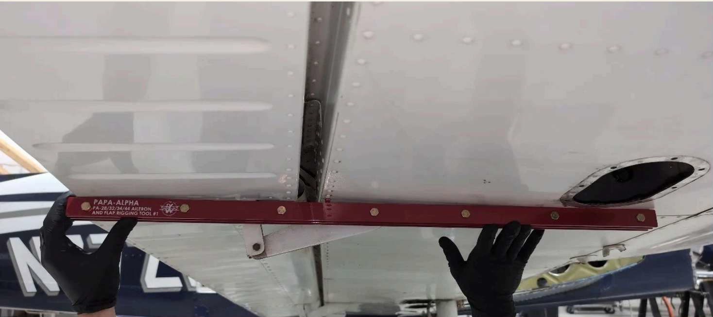 Papa Alpha flap-and-aileron rigging tool positioned on a Piper wing.